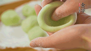 將均分的艾草面團搓成圓，挖一個窩，放入餡心，再搓成圓。