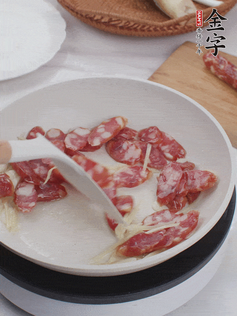 油溫3成熱時(shí)，下姜絲、蒜片、香腸炒出油脂。