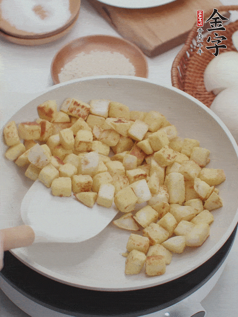 起鍋熱油，倒入饅頭丁，小火煎至蛋液凝固定型再翻面，饅頭丁部煎至金黃時盛起待用。