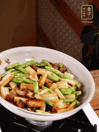 油熱下蒜末、干辣椒、醬肉煸炒出香味，依次下藕條、豆角翻炒均勻